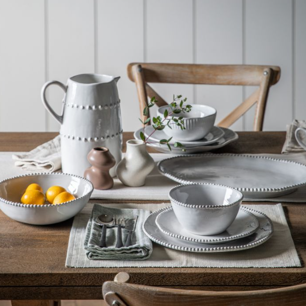 Dining table setting with ceramic dishes and a pitcher on a wooden table.