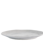 White ceramic dinner plate with ribbed detailing and soft rippled edge on a table setting