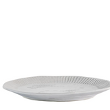 White ceramic dinner plate with ribbed detailing and soft rippled edge on a table setting