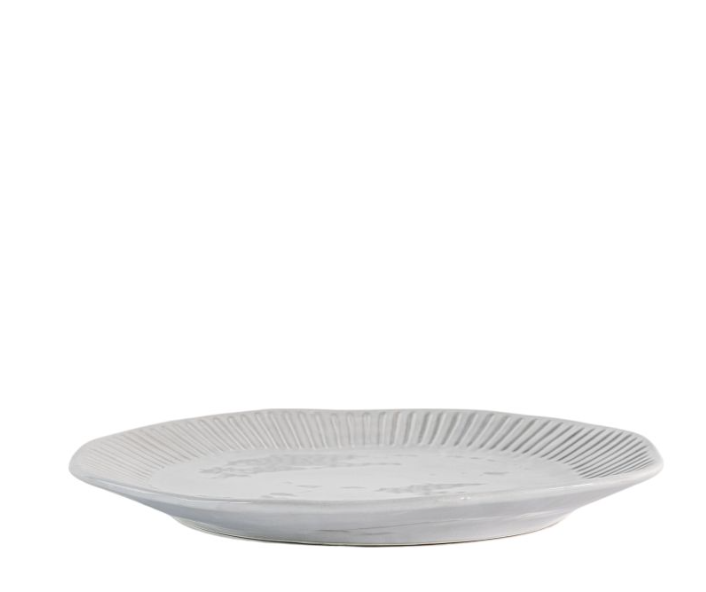 White ceramic dinner plate with ribbed detailing and soft rippled edge on a table setting