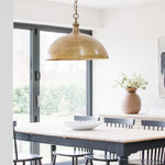 An oversized pendant light with a bronze finish hanging over a dining table in a room with a light color scheme.