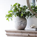 Stone pot styled with greenery on a wooden console table