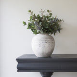 Stone pot styled with greenery on a wooden console table