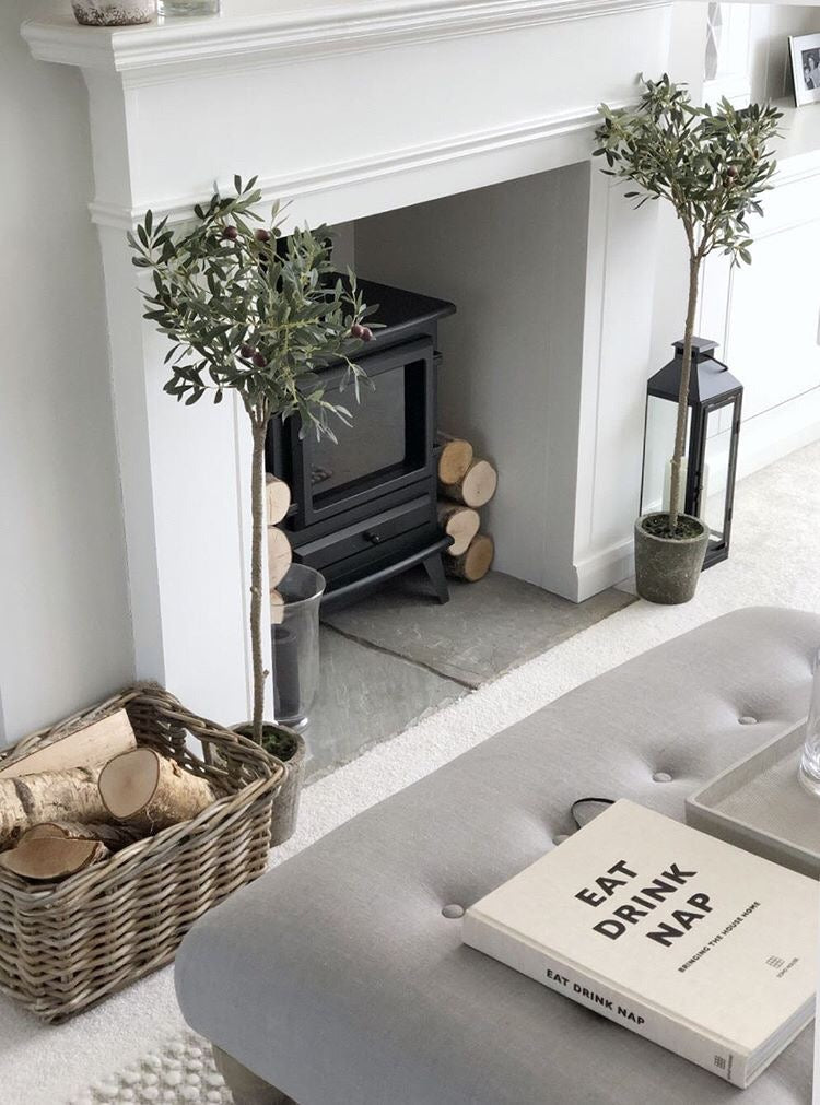 two faux olive trees flanking a fireplace