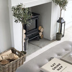 two faux olive trees flanking a fireplace