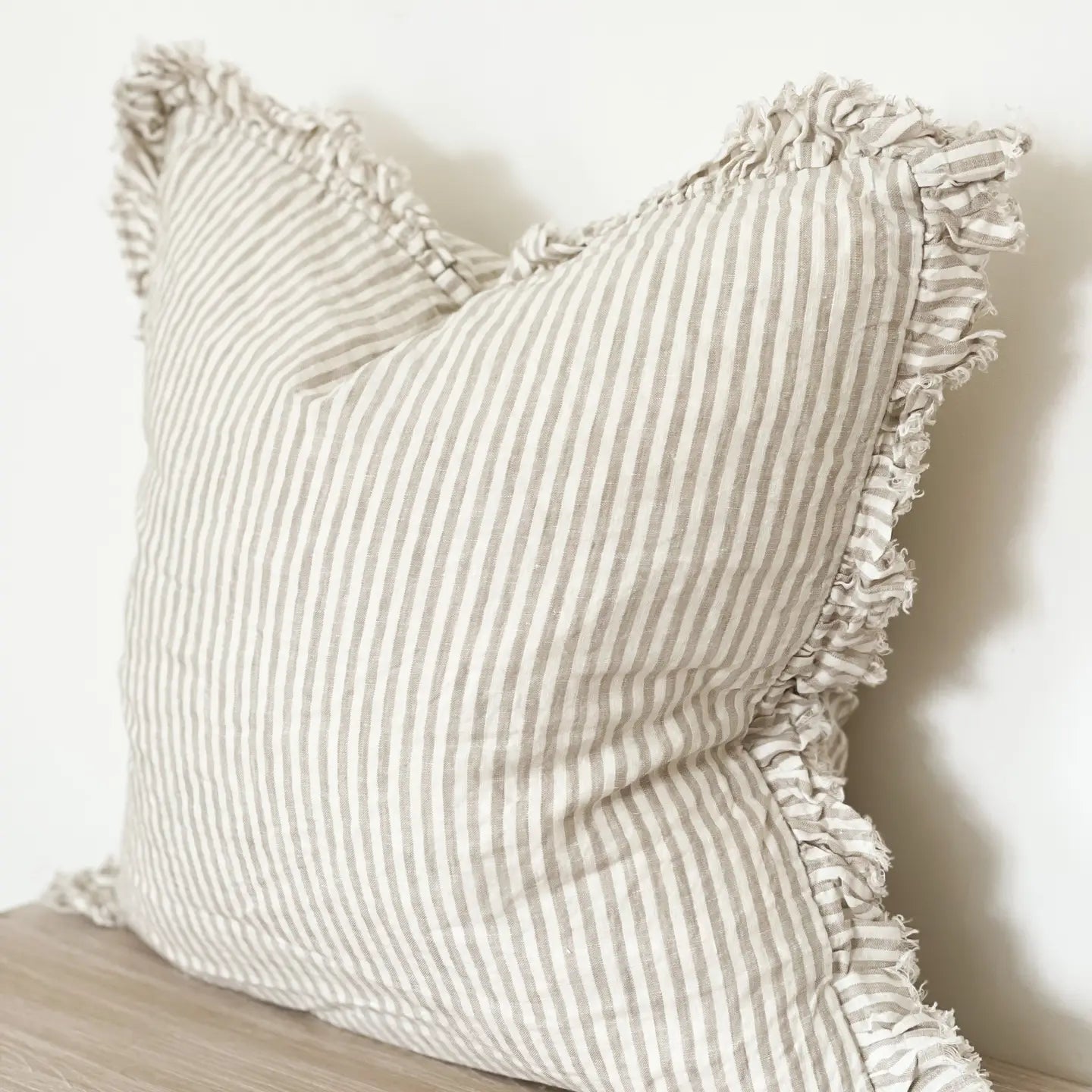 white and beige striped cushion with ruffled edges