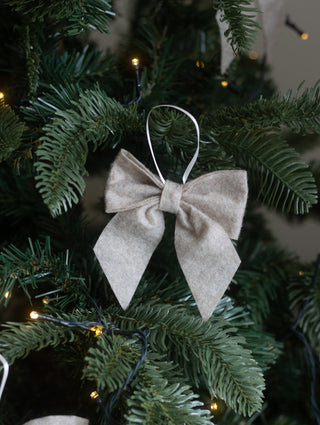 Small linen felt bow hanging on a Christmas tree branch with warm white lights