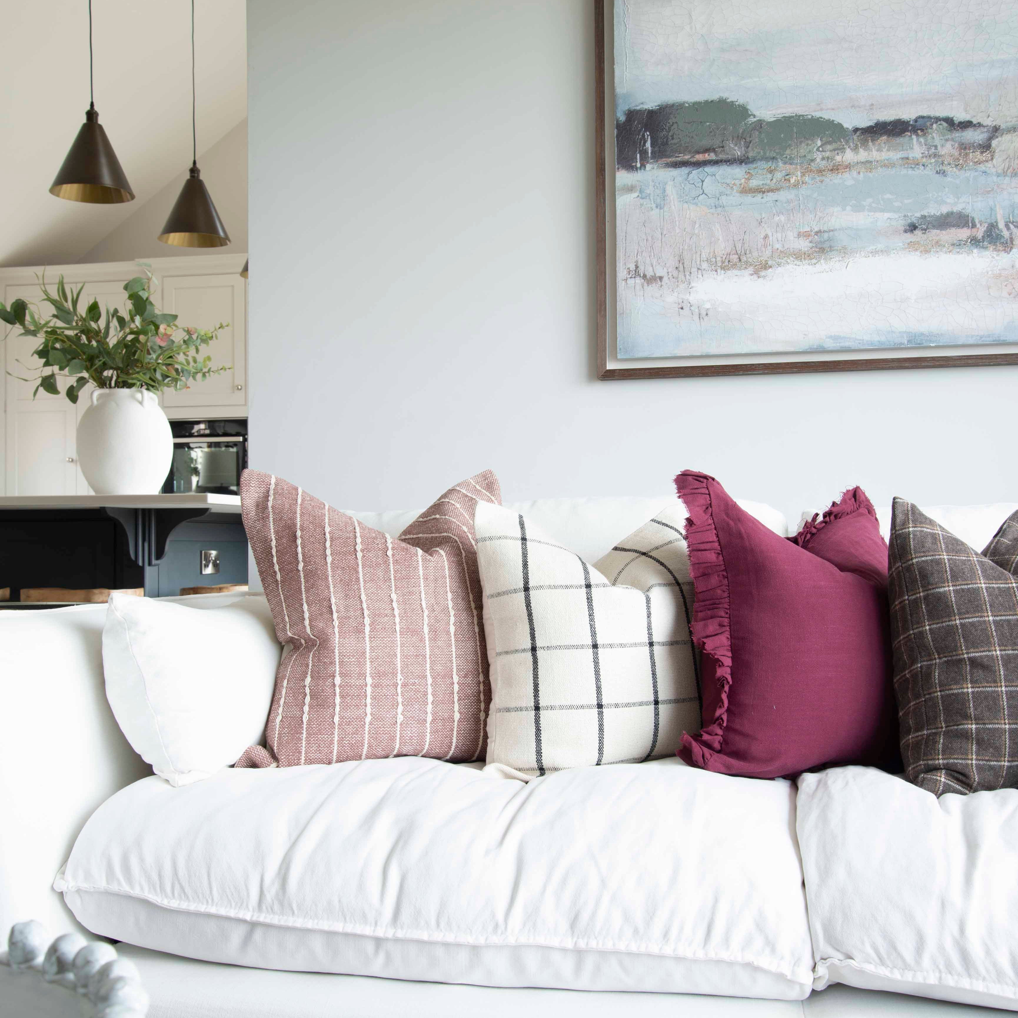 A stunning cotton cushion with a beautiful check detail arrayed on a white couch with other cushions