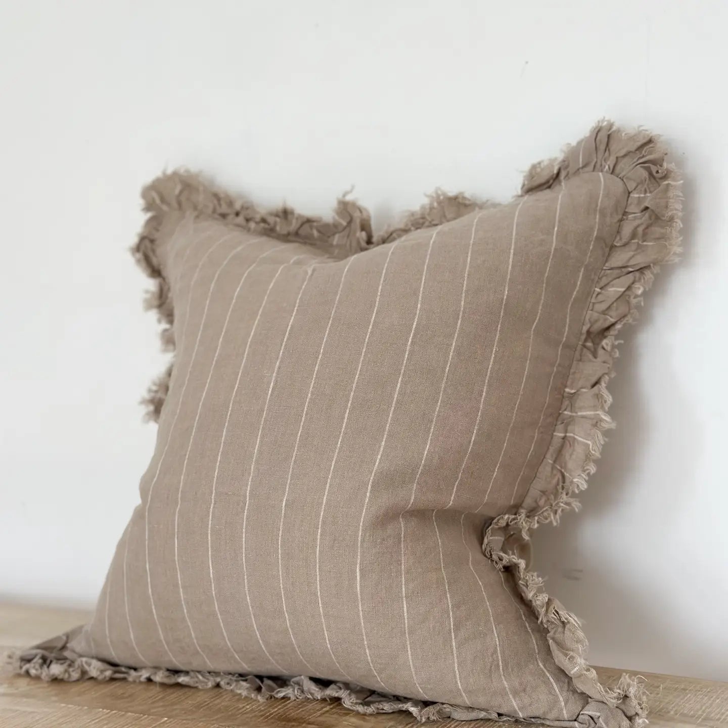 A beautiful linen cushion in taupe with white stripe running through and ruffled edges