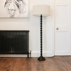 A stunning floor lamp in black featuring a beautiful turned base complete with off white linen shade.