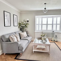 Wide angle of living room built around a coffee table crafted from acacia wood with a rattan and glass top.