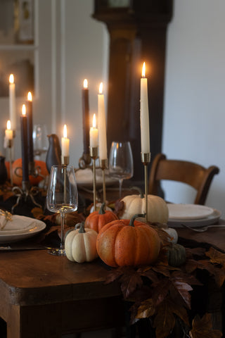 Rustic orange faux pumpkins styled among tall taper candles