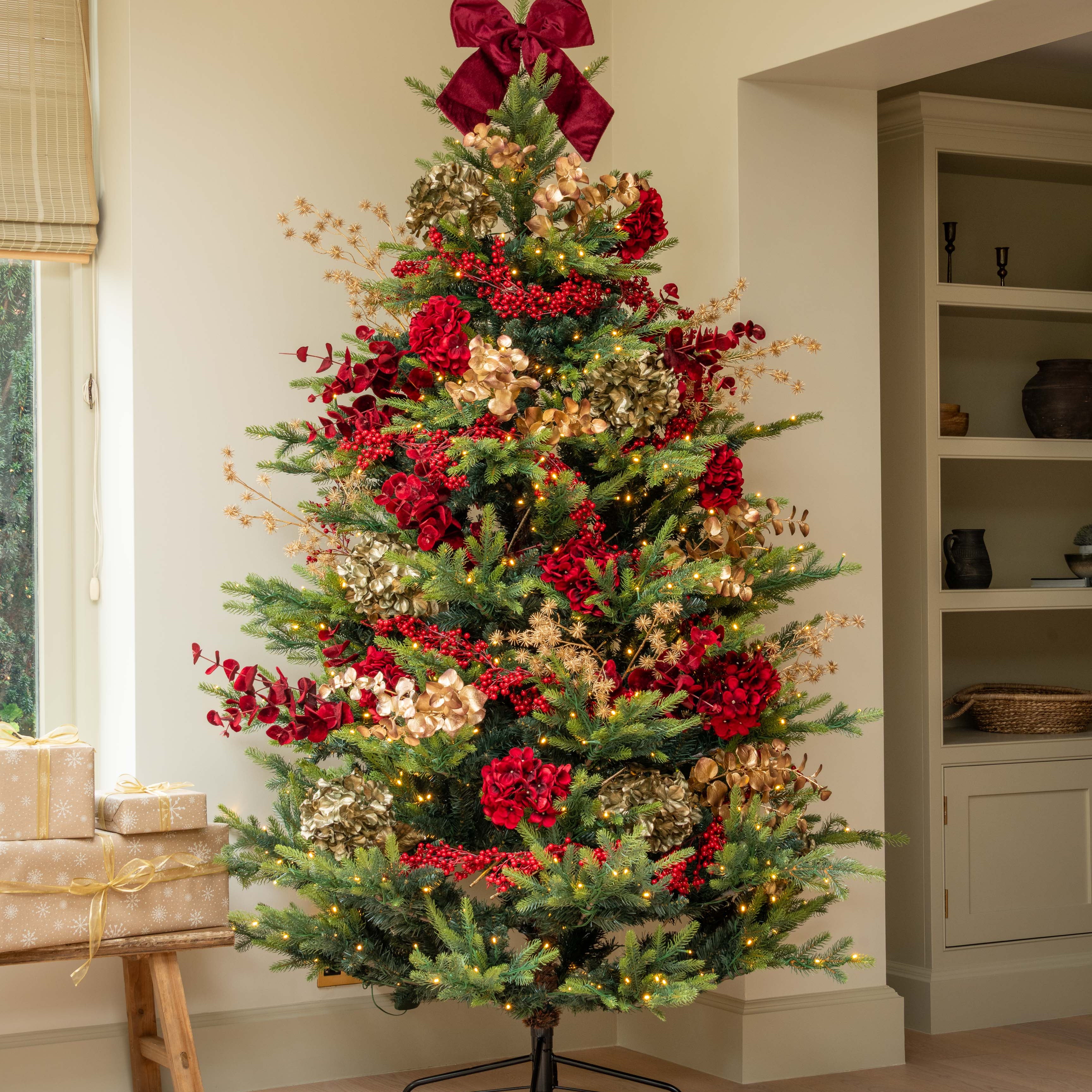 Decorated Christmas tree with red bows and ornaments in a room setting.