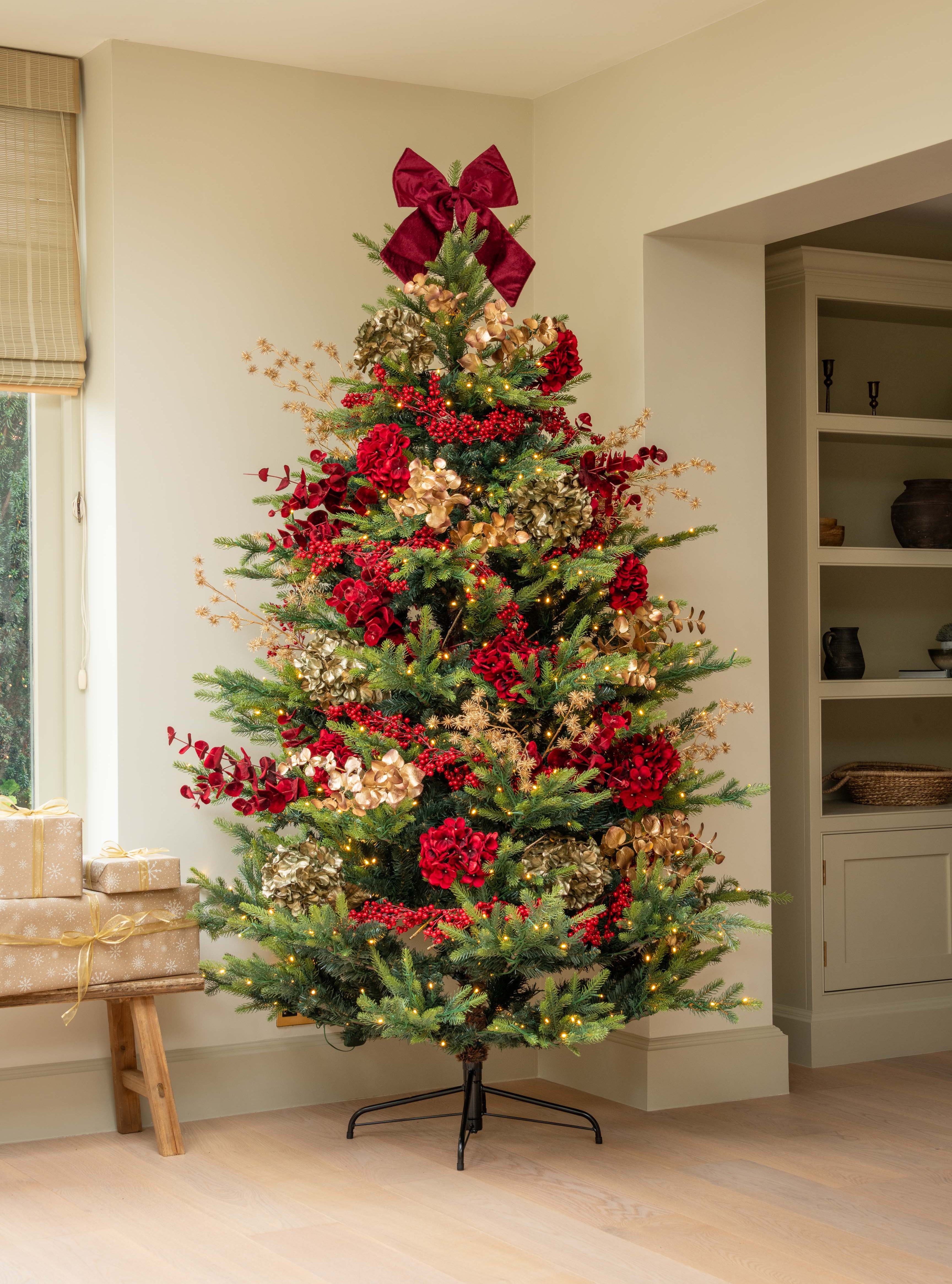 Decorated Christmas tree with red bows and ornaments in a room setting.