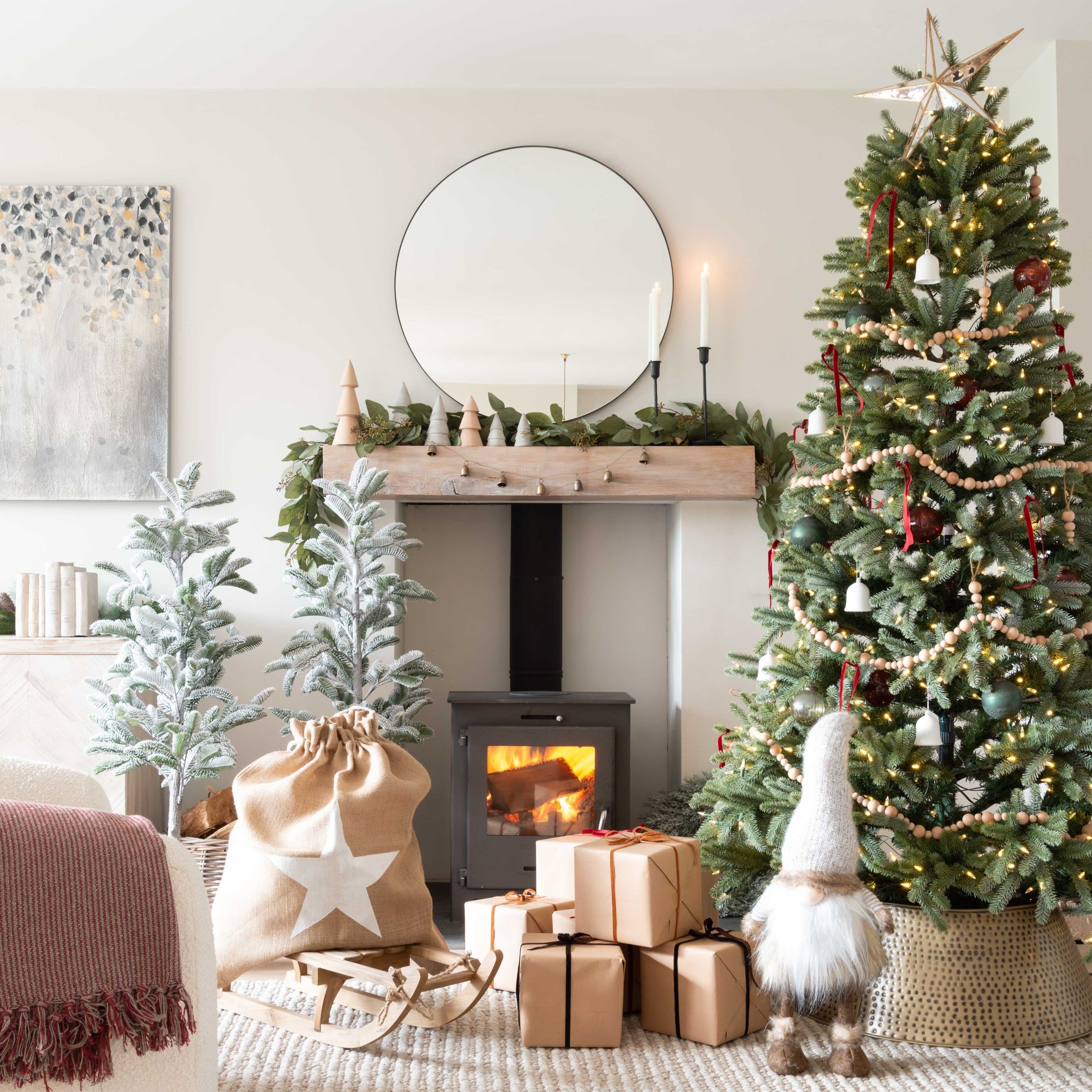 Cozy living room decorated for Christmas with a tree, presents, and fireplace.