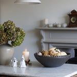 Decorative setup on a marble surface with a candle, bowl, and small figures.