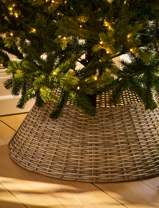 Grey rattan tree skirt around the base of a lit Christmas tree
