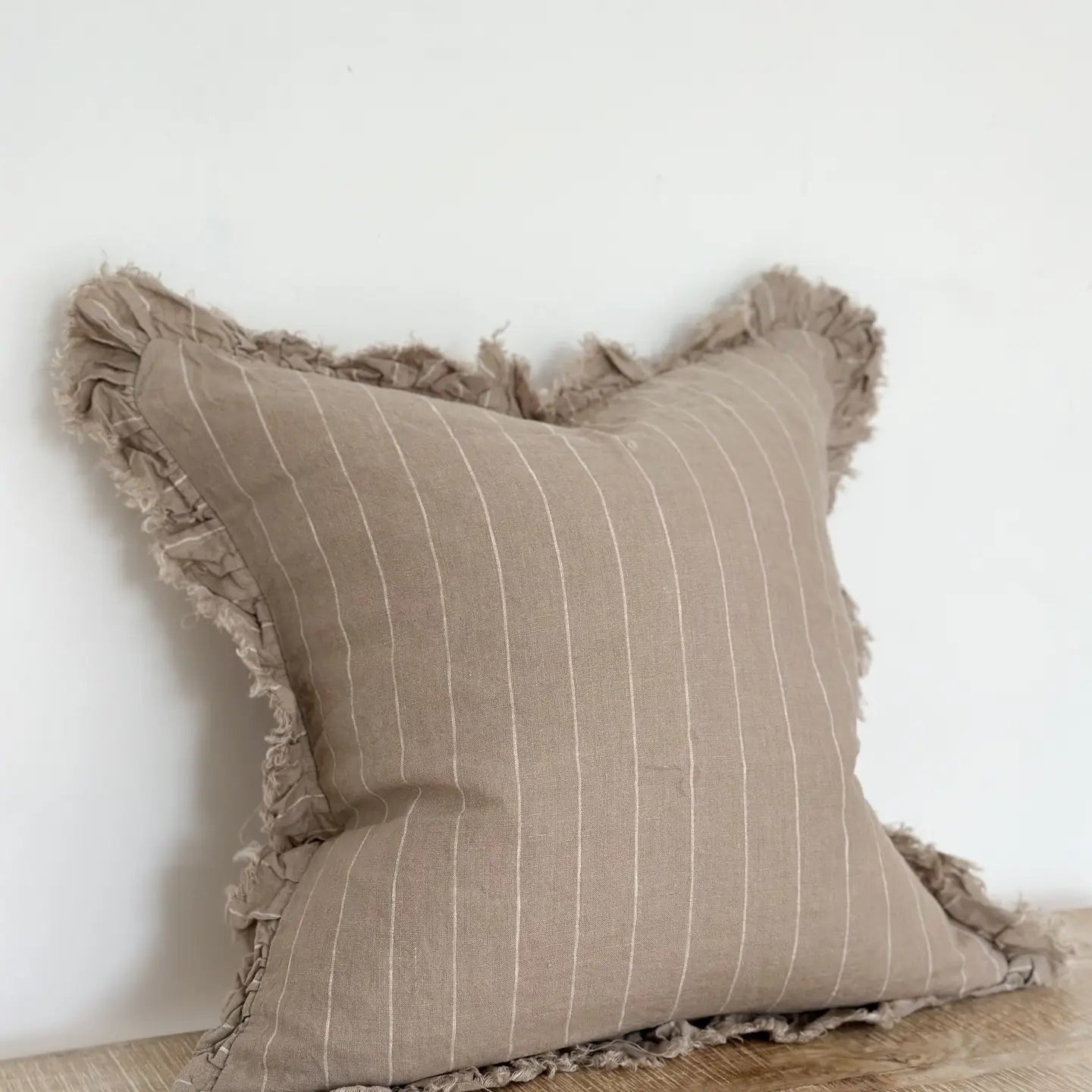 A beautiful linen cushion in taupe with white stripe running through and ruffled edges