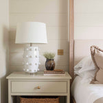  Crafted from sleek white ceramic and adorned with elegant bobble detailing, this lamp comes complete with a crisp white shade. 
