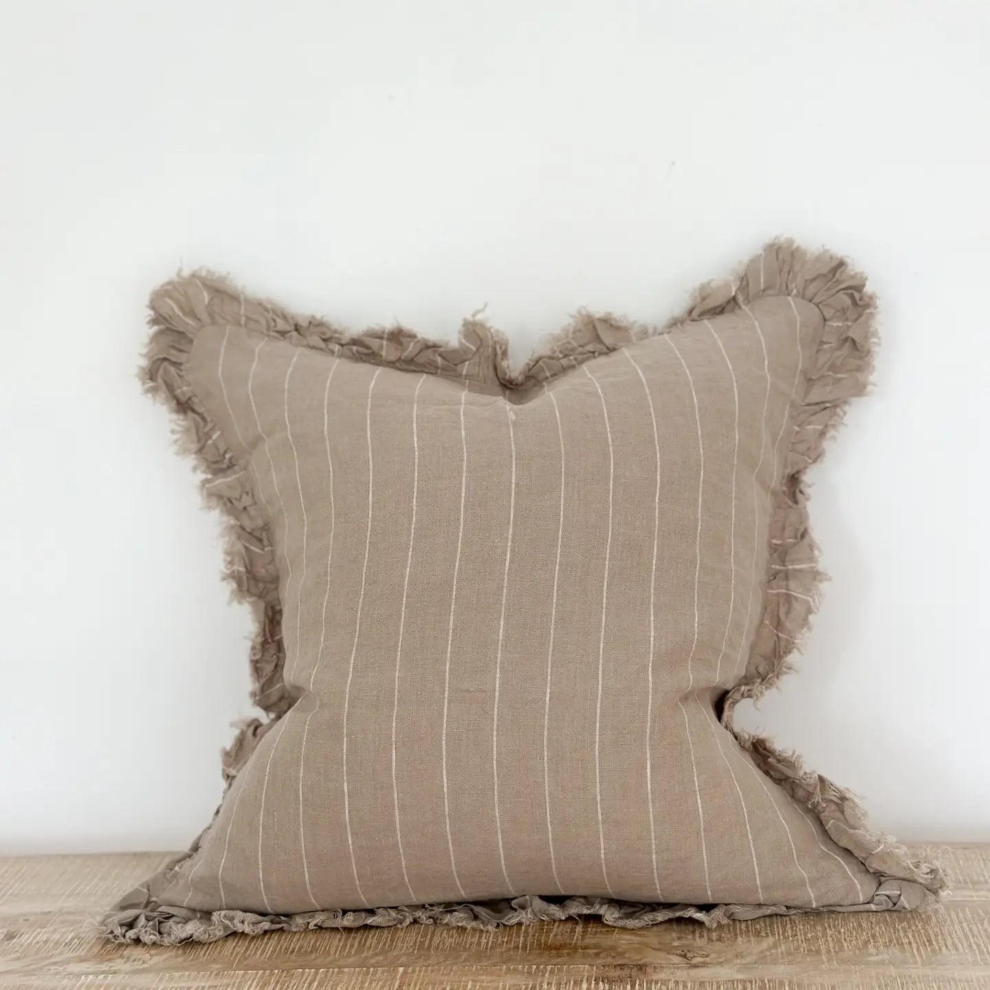 A beautiful linen cushion in taupe with white stripe running through and ruffled edges