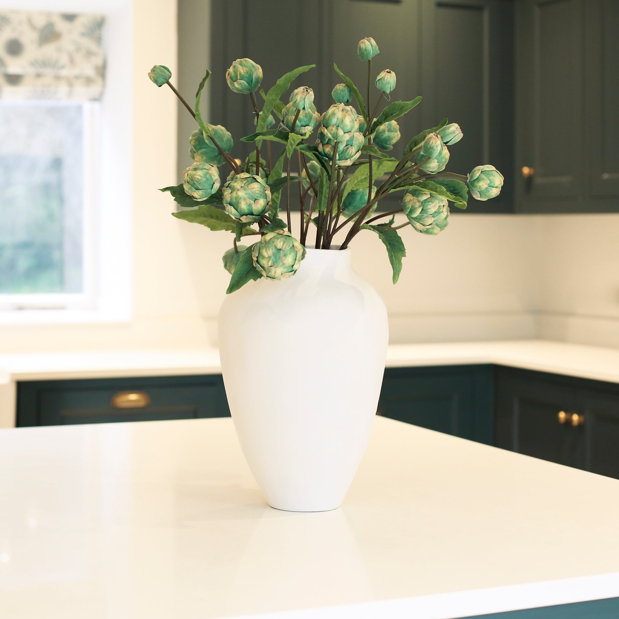 Artichoke stems in a tall white vase
