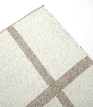 Close-up of Aldeburgh rug showing textured cream wool flatweave and soft taupe line