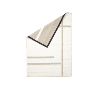 Aldeburgh wool rug with corner folded showing reversible weave and dark bound edge