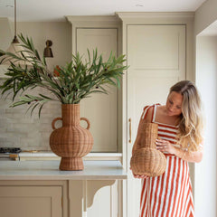 Handwoven with care and tradition, the Alderfield Jug brings the charm of rustic craftsmanship into your space. Inspired by heritage vessels once used to gather spring water or display wild blooms, this piece features a rounded base, tall neck, and two looped handles for a timeless silhouette. Made from natural rattan, its warm, earthy tones and intricate weave tell a story of simple living and enduring beauty. Whether placed on a farmhouse table or nestled in a sunlit corner, the Alderfield Jug adds textur