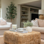 Living room with a woven ottoman, books, and a candle.