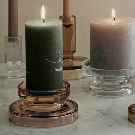 Candles in glass holders on a marble surface with a neutral background