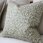 Olive green cotton cushion cover with white leaf pattern on a neutral sofa