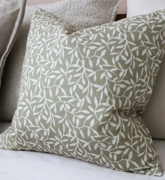 Olive green cotton cushion cover with white leaf pattern on a neutral sofa