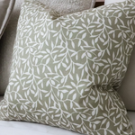 Olive green cotton cushion cover with white leaf pattern on a neutral sofa