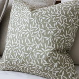 Olive green cotton cushion cover with white leaf pattern on a neutral sofa