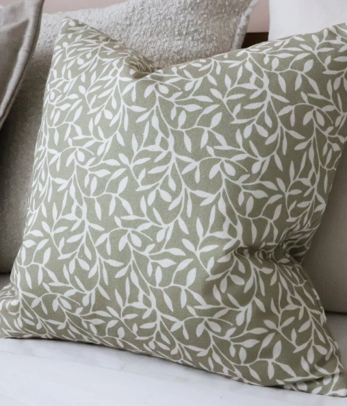 Olive green cotton cushion cover with white leaf pattern on a neutral sofa