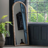 Arched full-length mirror styled in a rustic room with greenery and natural light