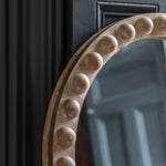 Close-up of carved beaded wood detailing on arched mirror frame