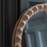 Close-up of carved beaded wood detailing on arched mirror frame