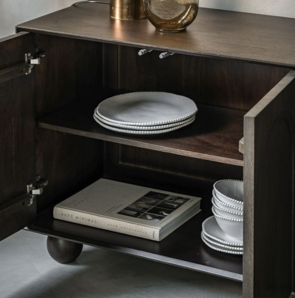 Wooden cabinet with open door displaying plates and a book on a neutral background