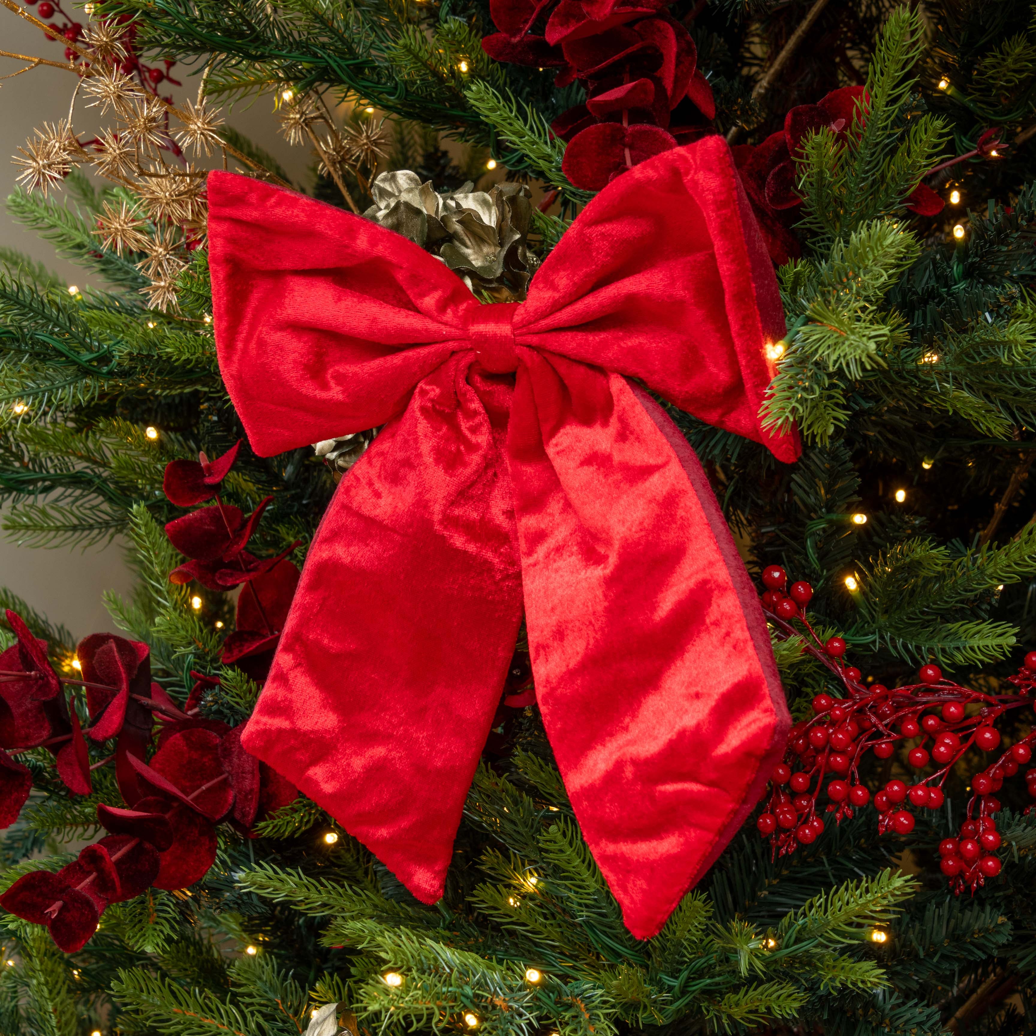 Decorative red bow on a Christmas tree with lights and ornaments.