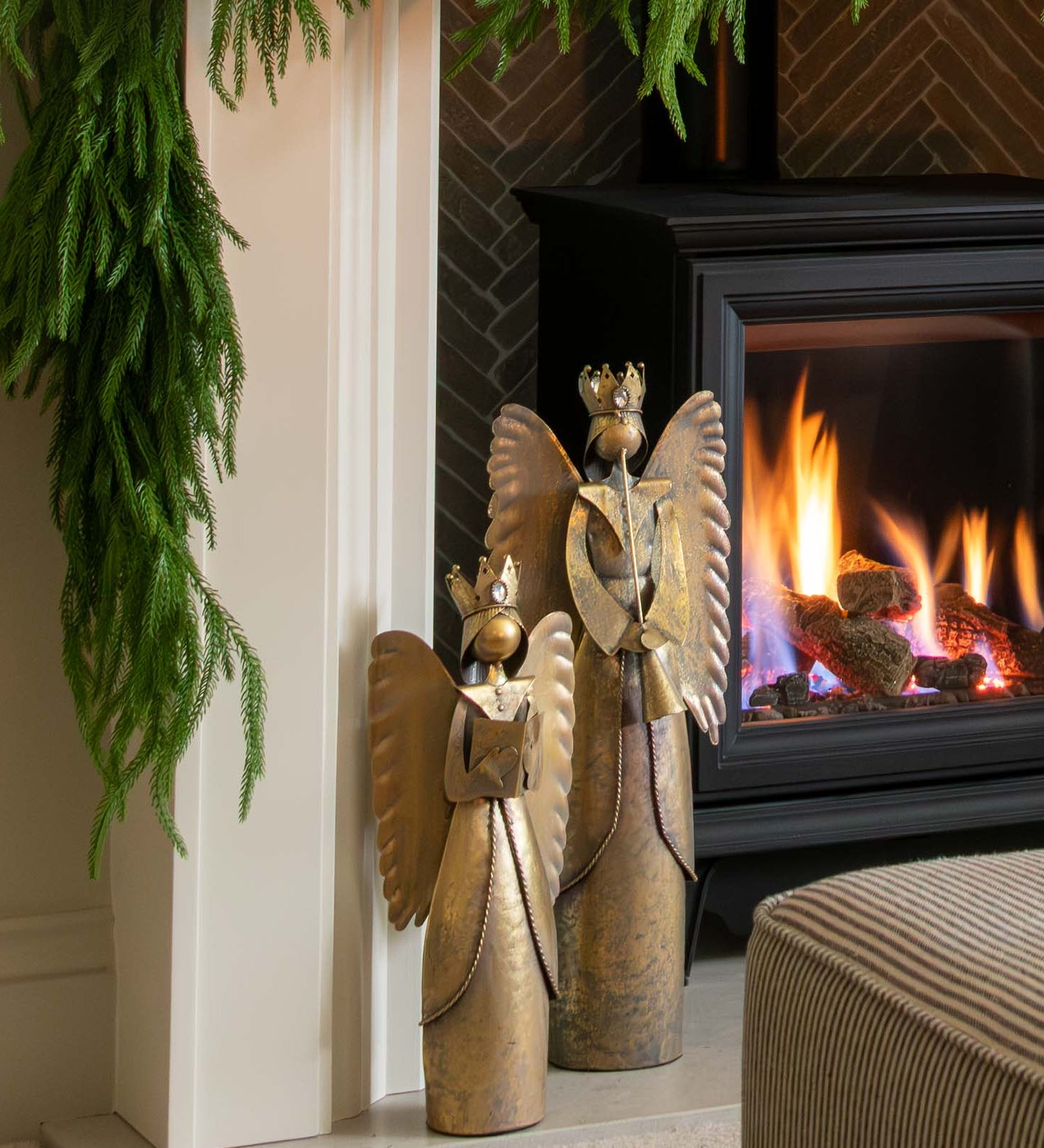 Decorated fireplace with greenery and a candle, framed artwork above, and a cozy living room setting.