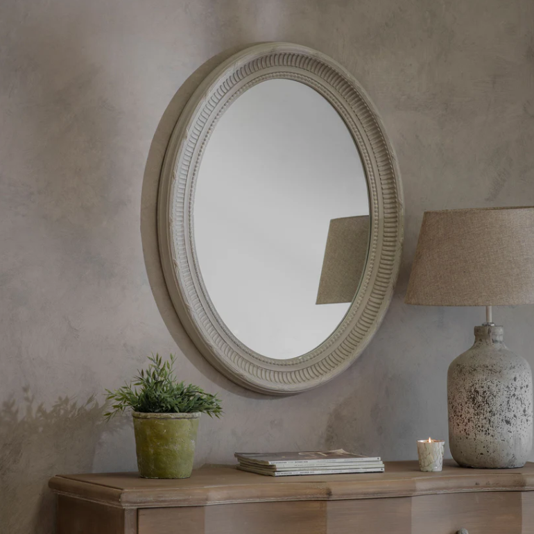 The Bennett Oval Mirror with detailed beaded frame and soft neutral finish, styled above a wooden console with lamp and candle décor.