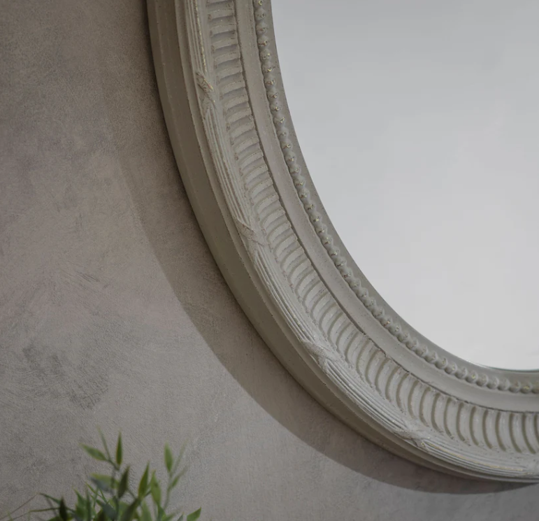 The Bennett Oval Mirror with detailed beaded frame and soft neutral finish, styled above a wooden console with lamp and candle décor.