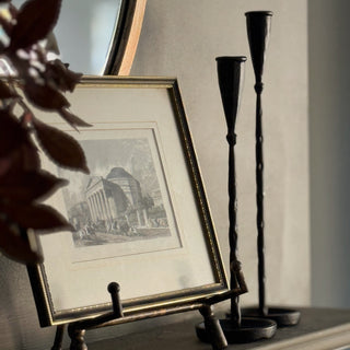 mantlepiece styled with picture in an easel and two black metal candlesticks