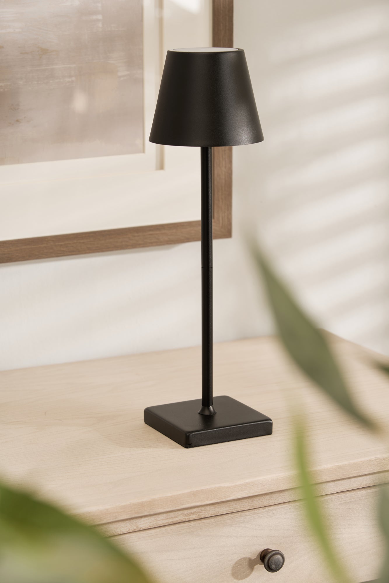 A sleek black wireless lamp on a wooden surface with a USB-C cable visible in the image.