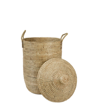 A natural woven seagrass or straw storage basket with two side handles and a matching round conical lid, shown on a plain white background.