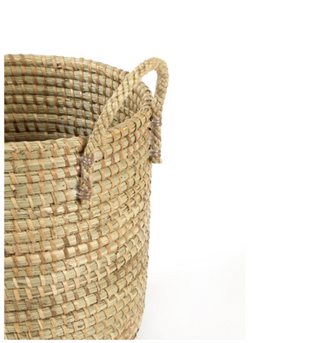 Close-up of a woven natural fiber basket with two loop handles on a plain white background.