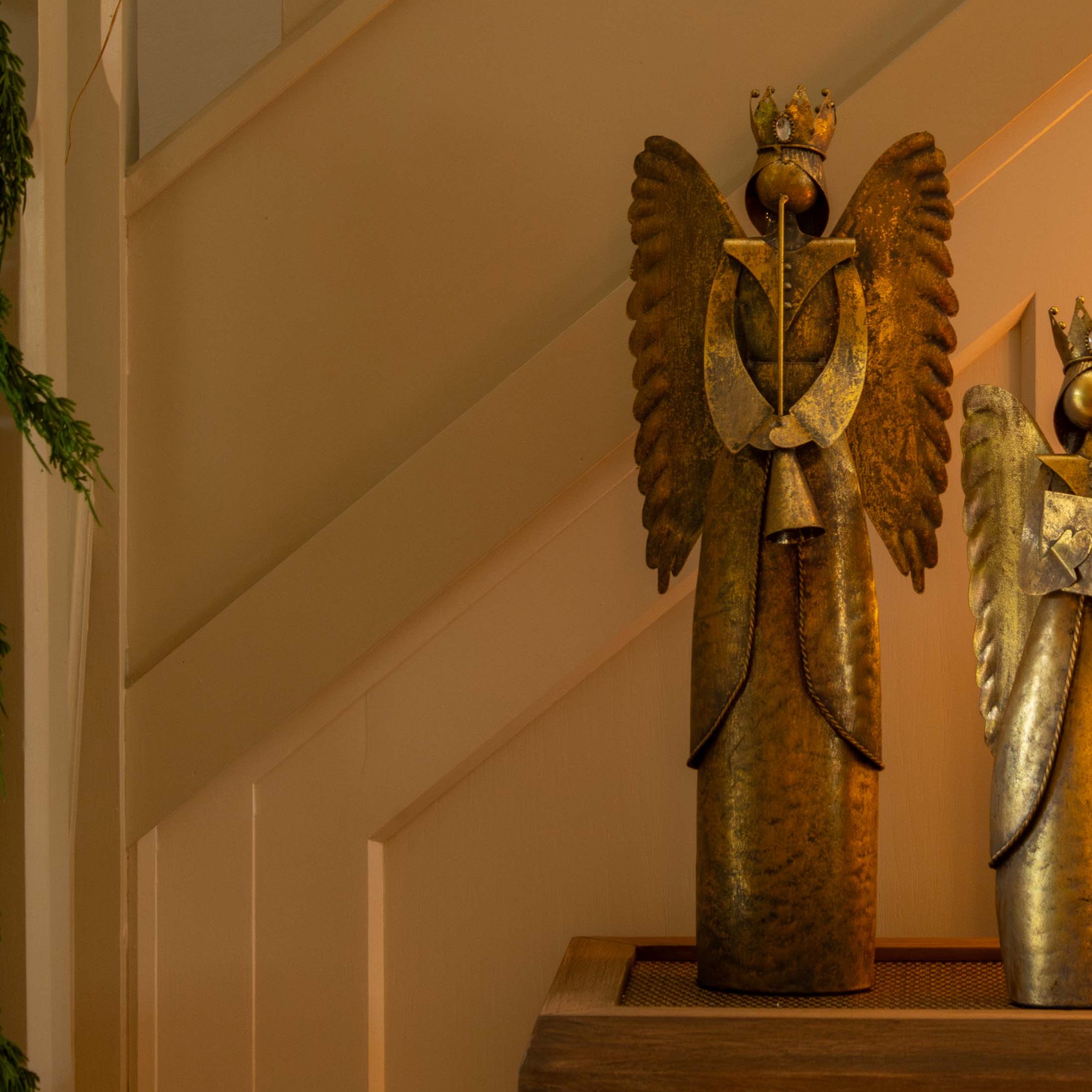 Decorative angel figurine with gold wings on a shelf next to books and a candle.