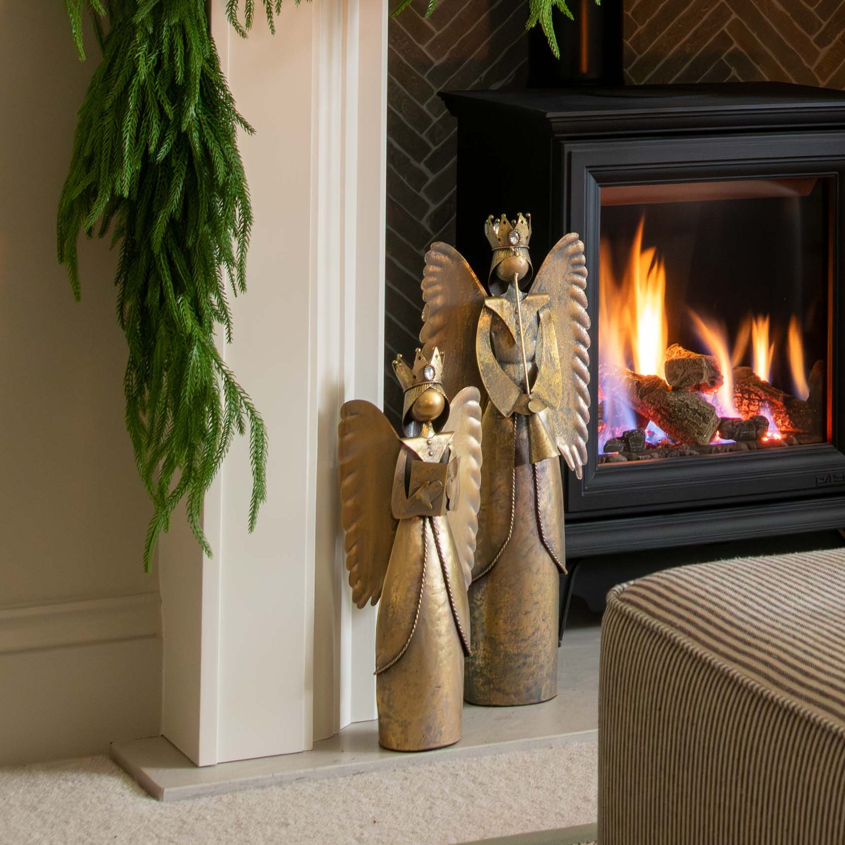 Decorated fireplace with greenery and a candle, framed artwork above, and a cozy living room setting.