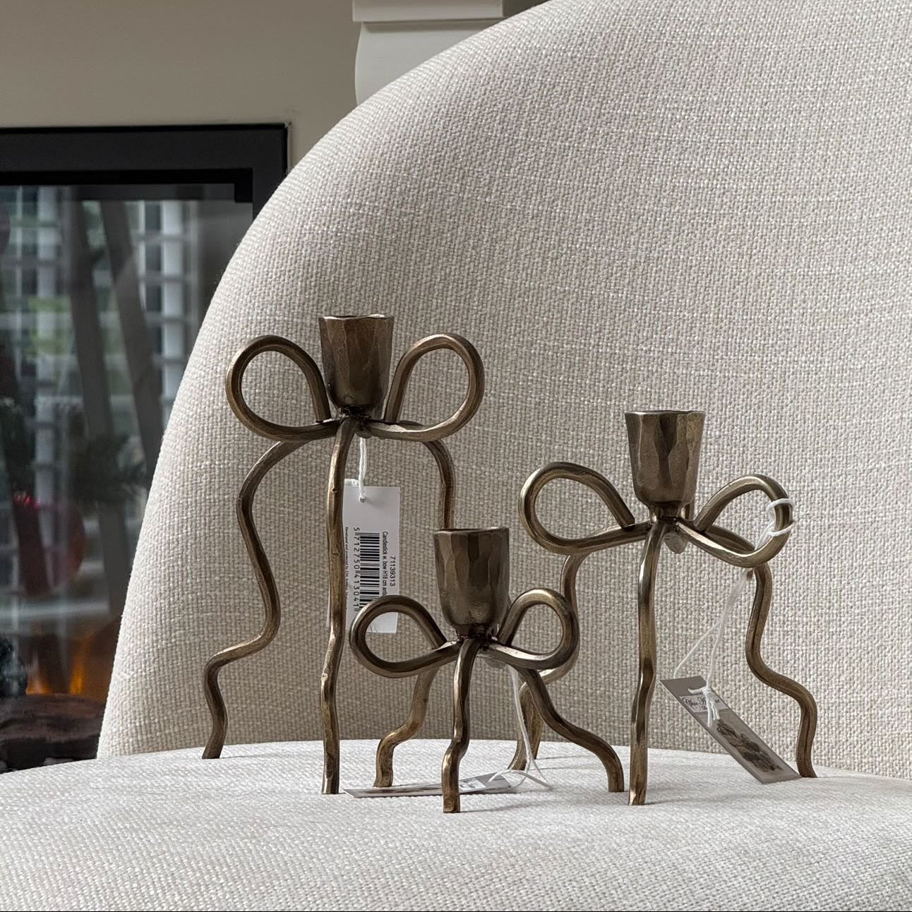 Bronze candle holders on a textured surface with a fireplace in the background